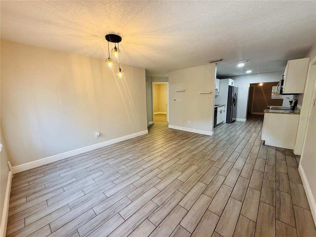 An open-concept dining area features light wood-look tile flooring and a modern three-light pendant fixture — 4203 E YUKON STREET, TAMPA, FL