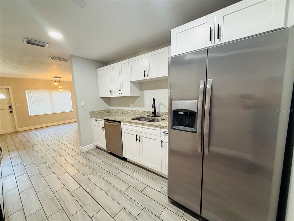 A kitchen features white cabinets, stainless steel appliances, and light-colored wood-look tile flooring — 4203 E YUKON STREET, TAMPA, FL
