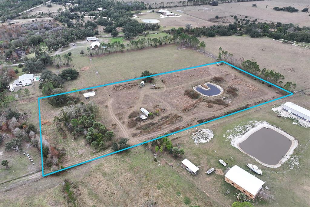 An aerial view shows a fenced rural property featuring a small pond and outbuildings — 14780 SUGAR BOWL ROAD, MYAKKA CITY, FL