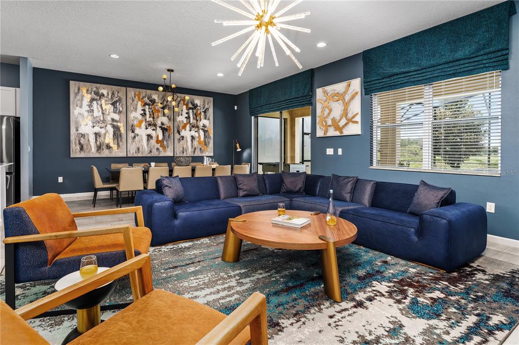 A living room features a large blue sectional, two orange chairs, and a round coffee table — 8009 OAK SHADOW COURT, DAVENPORT, FL
