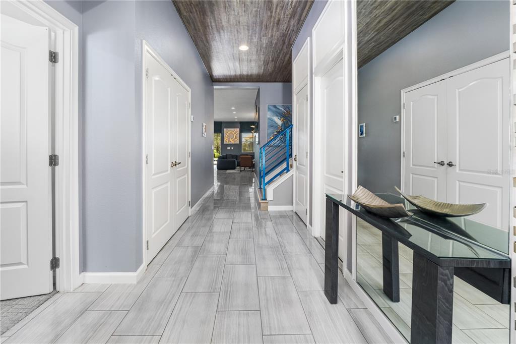 A hallway features light gray tile flooring, a wood-paneled ceiling, and a glass console table — 8009 OAK SHADOW COURT, DAVENPORT, FL