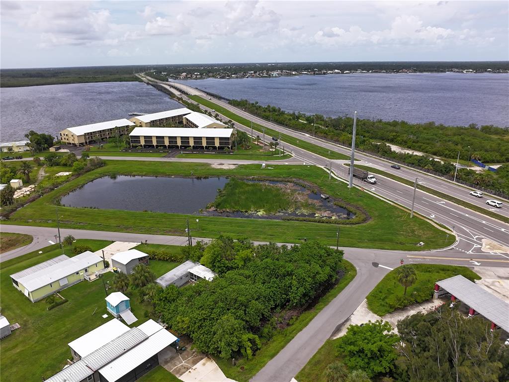 An aerial view shows a pond, a multi-story building, and a highway bridge over water — 4572 STURKIE AVENUE, PORT CHARLOTTE, FL
