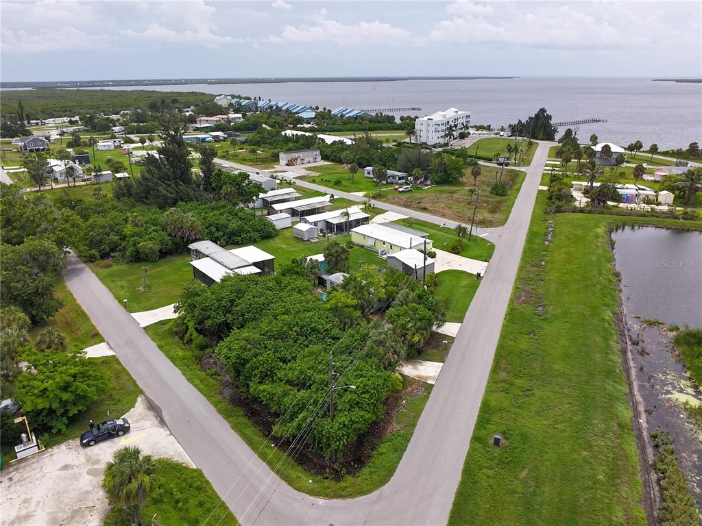 An aerial view shows a residential area with mobile homes, trees, and a nearby body of water — 4572 STURKIE AVENUE, PORT CHARLOTTE, FL