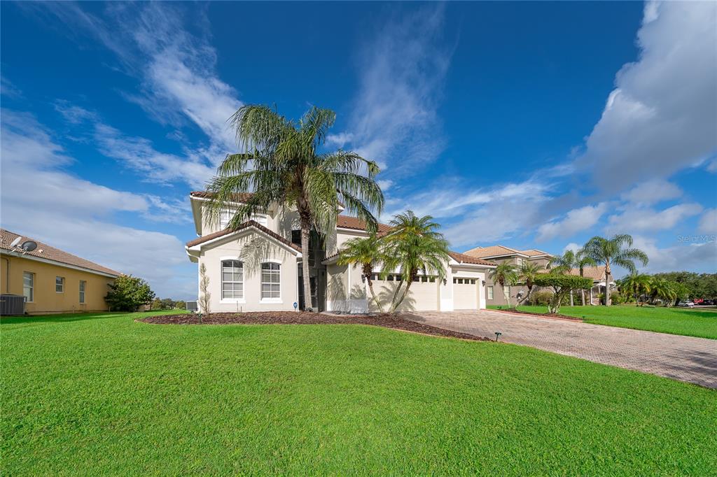 A two-story suburban house with a paved driveway, palm trees, and a green lawn — 3426 HARBORSIDE COURT, KISSIMMEE, FL