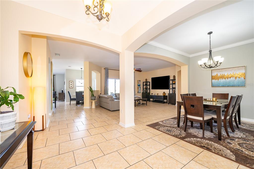 An open-concept living and dining area with tile flooring, arched doorways, and a chandelier — 3426 HARBORSIDE COURT, KISSIMMEE, FL