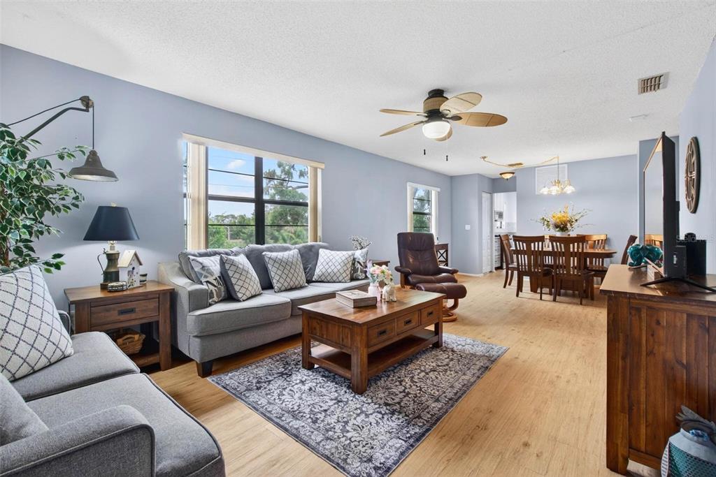 A living room with light blue walls, gray sofas, a wooden coffee table, and wood flooring — 5975 TERRACE PARK DRIVE N UNIT 311, ST PETERSBURG, FL