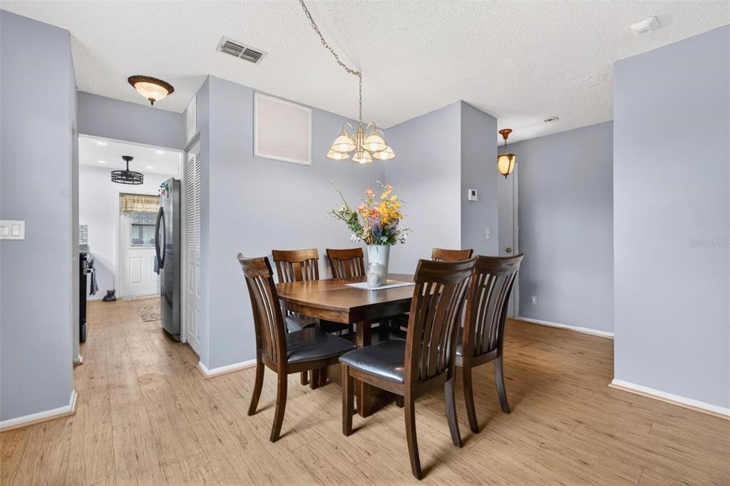 A dining area features a wooden table with six chairs, light blue walls, and wood flooring — 5975 TERRACE PARK DRIVE N UNIT 311, ST PETERSBURG, FL