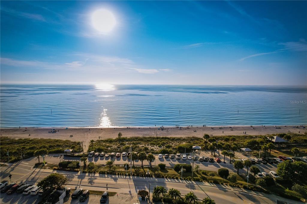 An aerial view shows a beach, ocean, and parking lot under a bright sun — 142 SUNNY WAY, ROTONDA WEST, FL