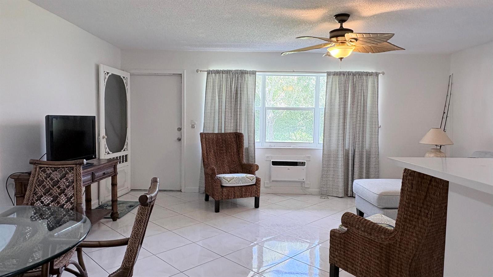 A living room features tiled floors, wicker furniture, a ceiling fan, and a window — 200 Horizon W # 102, Boynton Beach FL 33435, BOYNTON BEACH, FL