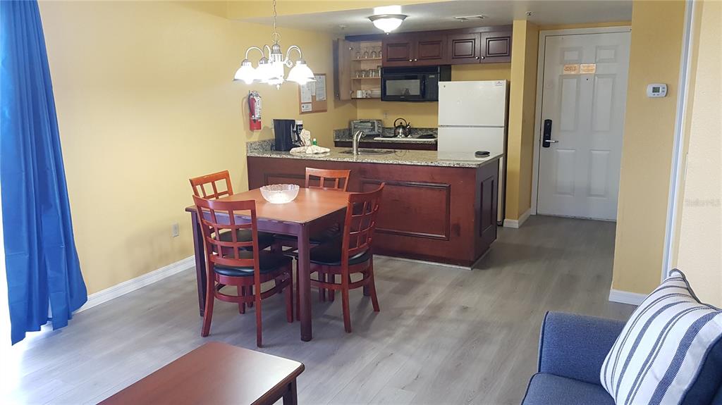 A dining area and kitchen with dark wood cabinets, granite countertops, and light flooring — 6403 PARC CORNICHE DRIVE UNIT 4107, ORLANDO, FL