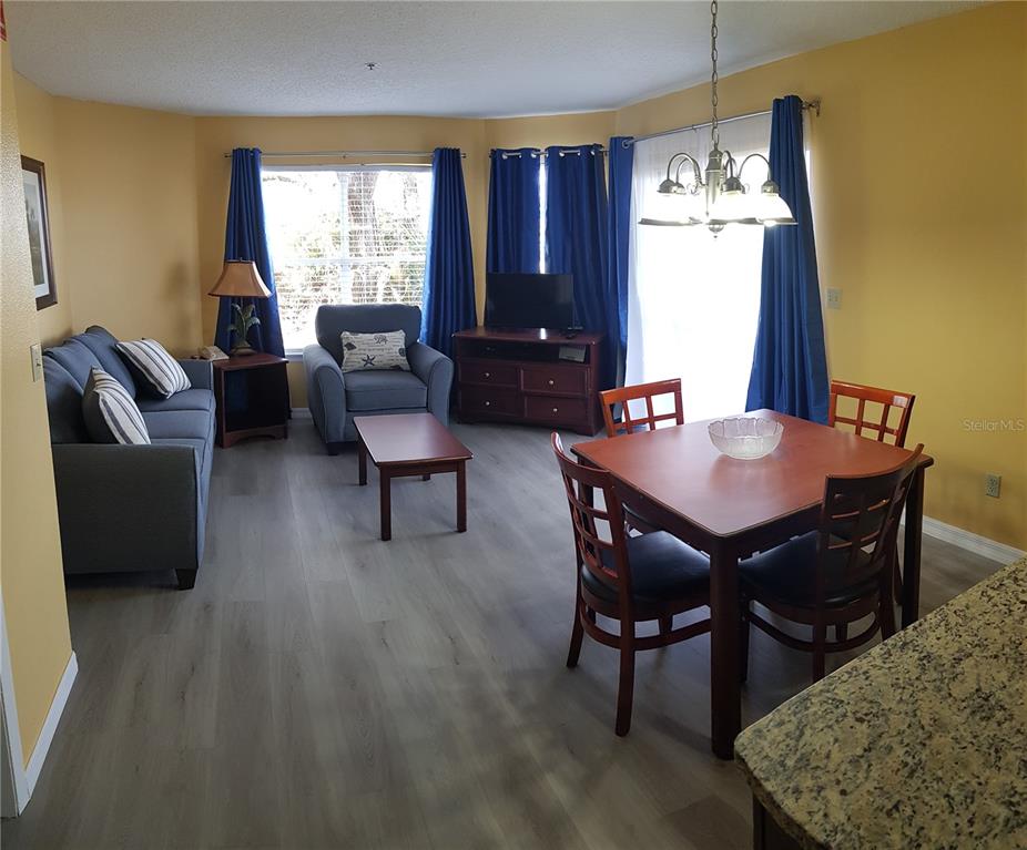 A living and dining area features yellow walls, gray flooring, and blue curtains — 6403 PARC CORNICHE DRIVE UNIT 4107, ORLANDO, FL