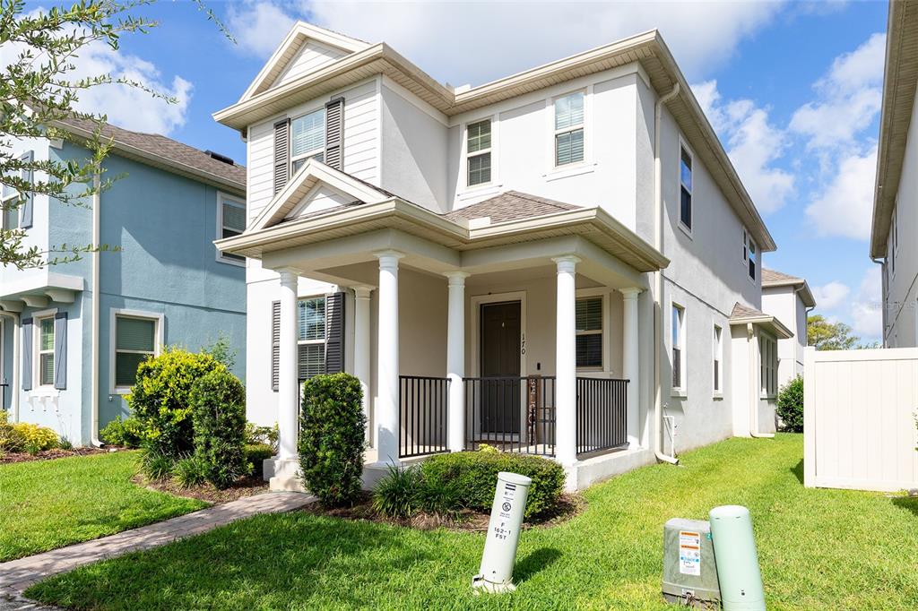 A two-story house with a white exterior, a covered front porch, and a small lawn — 170 WOODED VINE DRIVE, WINTER SPRINGS, FL