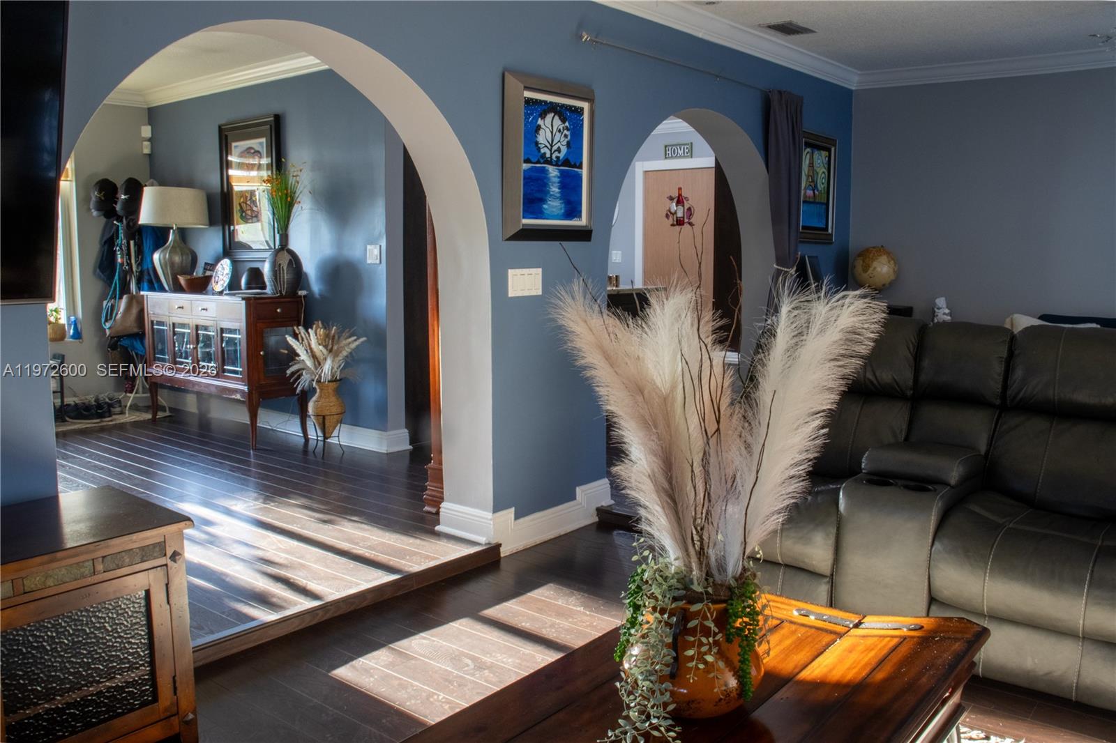 A living room features arched doorways, blue walls, dark wood floors, and a leather sofa — 17221 NW 82nd Ave, Hialeah FL 33015, HIALEAH, FL