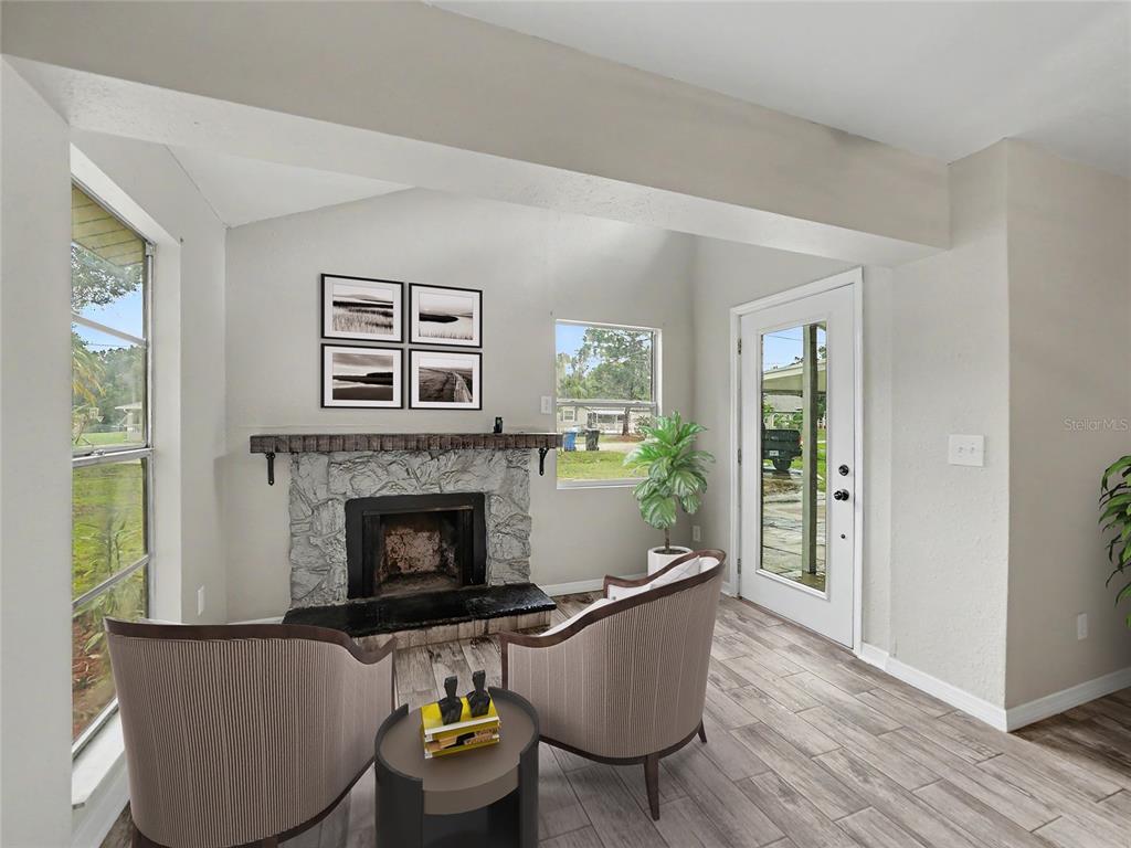 A living room features a stone fireplace, two armchairs, a small table, and a glass door — 2409 11TH AVENUE SE, RUSKIN, FL