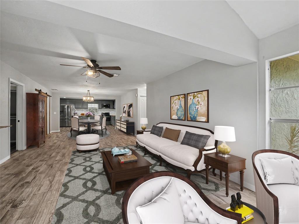 An open-concept living and dining area features wood-look tile flooring and a neutral color palette — 2409 11TH AVENUE SE, RUSKIN, FL