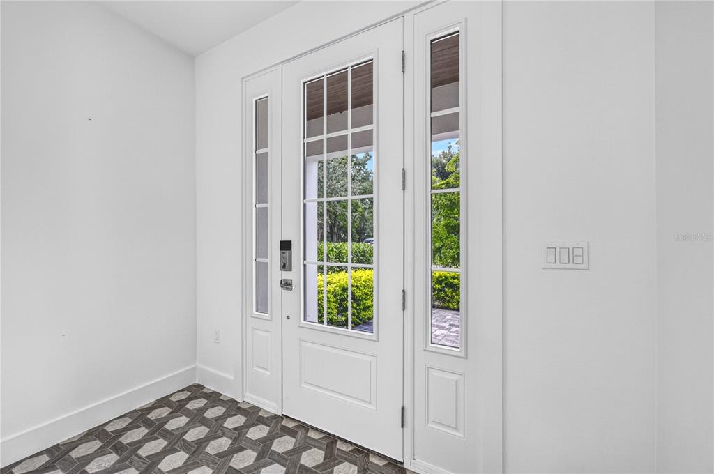A white front door with glass panels and sidelights opens into a tiled entryway — 2590 FLOYD STREET, SARASOTA, FL