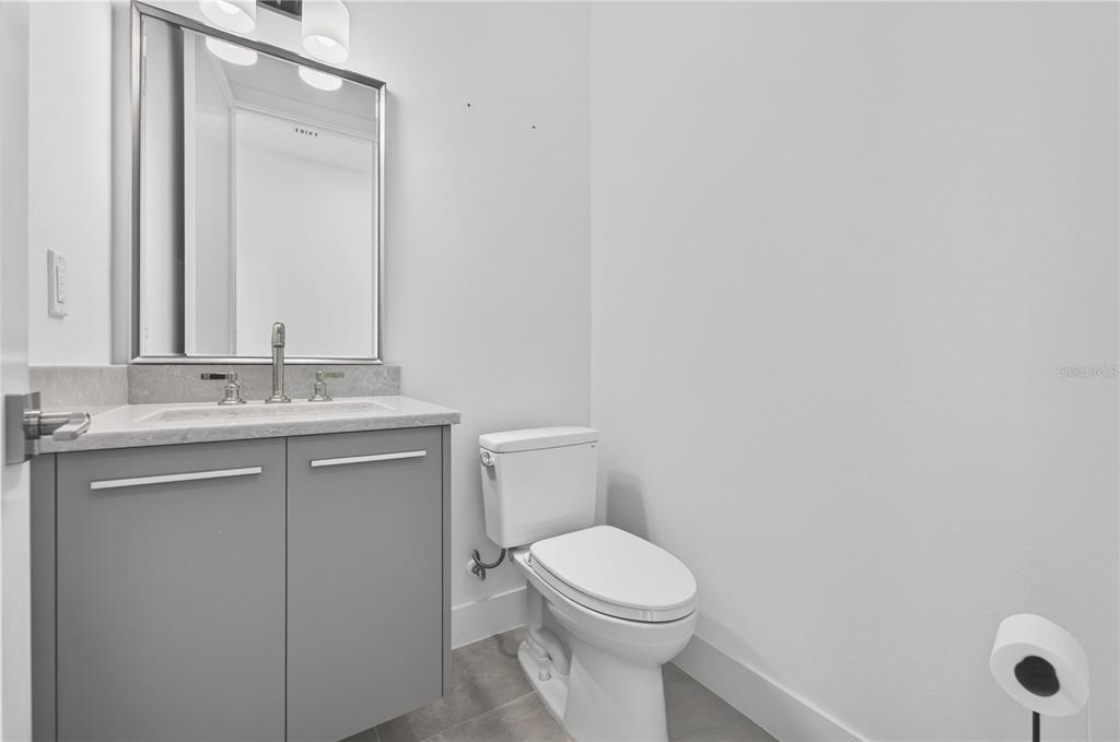 A modern half bathroom features a gray vanity, white countertop, and a wall-mounted mirror — 2590 FLOYD STREET, SARASOTA, FL
