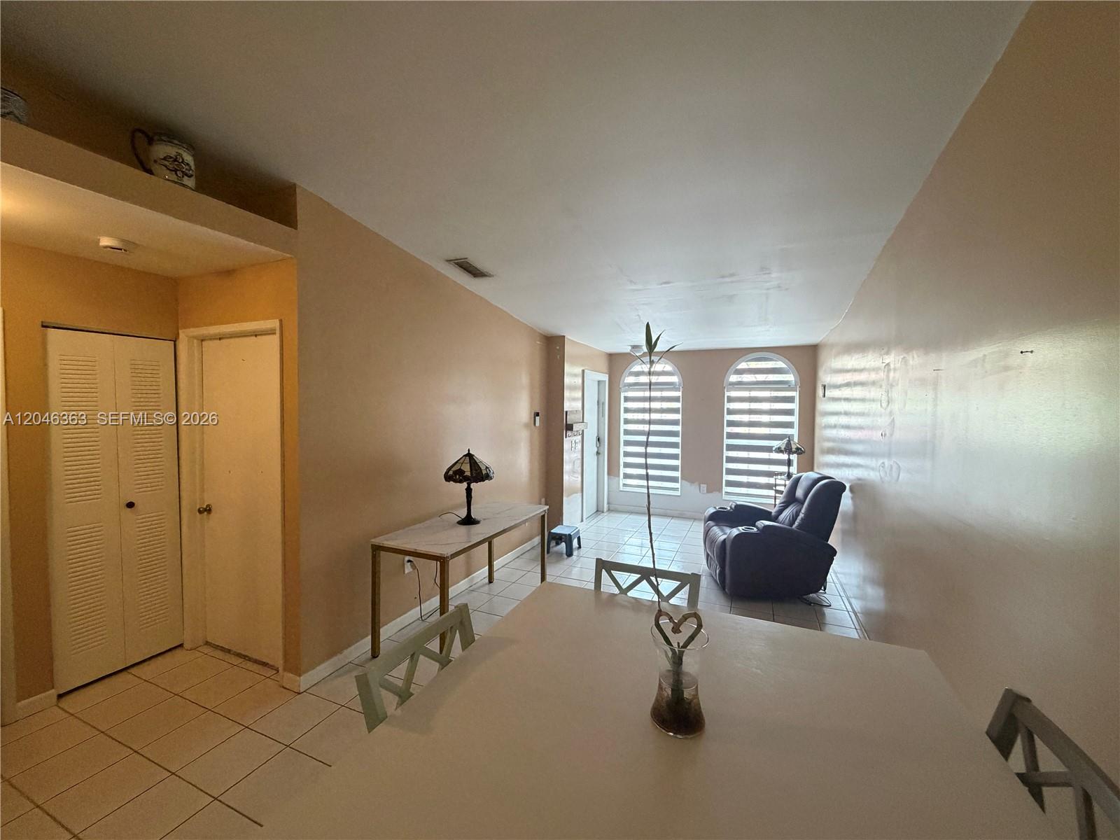 This living and dining area features tiled floors, beige walls, and two arched windows — 6718 NW 166th Ter # 301, Miami Lakes FL 33014, MIAMI LAKES, FL