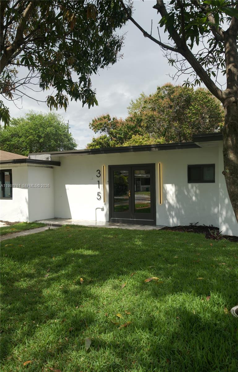 The exterior of a white, single-story house features a dark double-door entrance and address numbers — 315 NW 127th St, North Miami FL 33168, NORTH MIAMI, FL