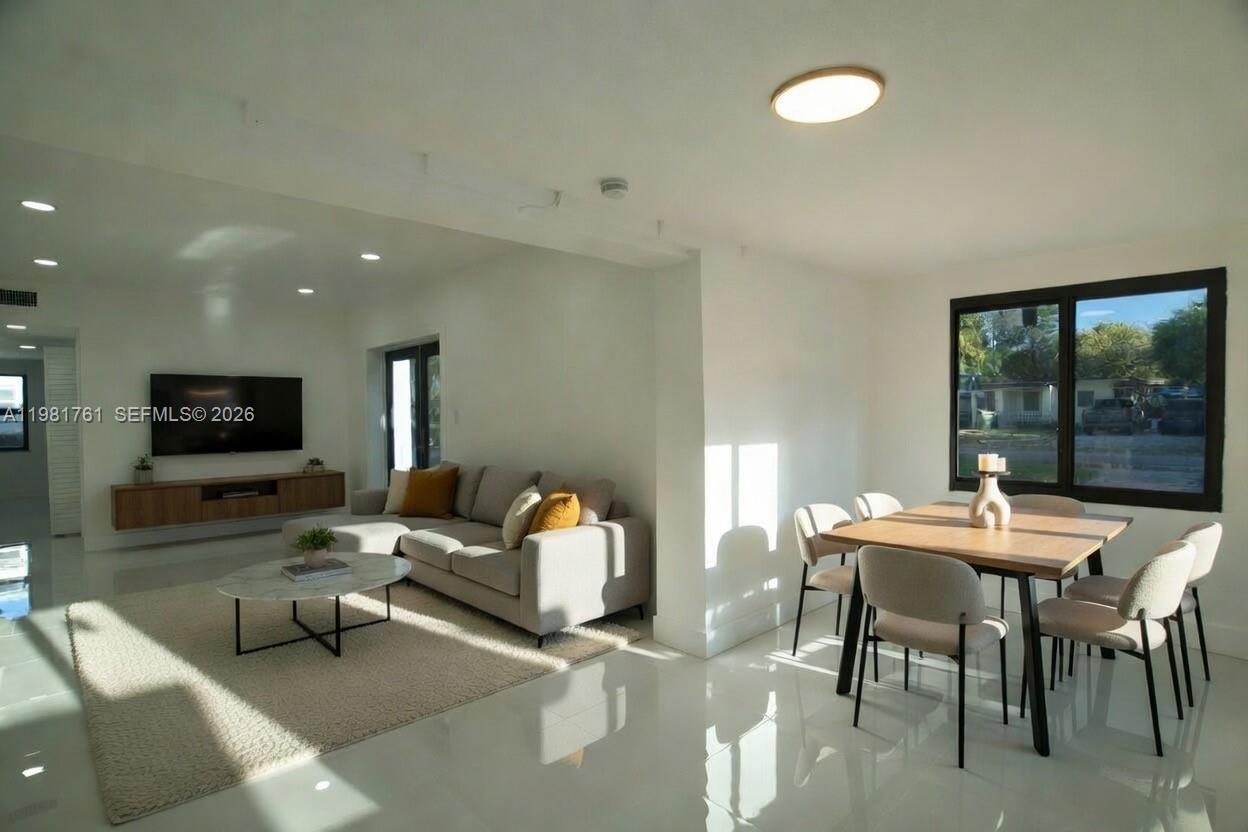 A bright, open-concept living and dining area features white walls, tile floors, and modern furniture — 315 NW 127th St, North Miami FL 33168, NORTH MIAMI, FL