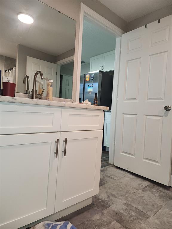 A bathroom vanity with a white cabinet and marble countertop sits next to a closed door — 2439 LAKEVIEW STREET, LAKELAND, FL