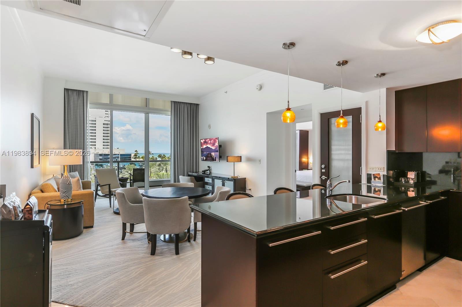 An open-concept living area features a kitchen with dark cabinetry, a dining table, and balcony — 4391 Collins Ave, Miami Beach FL 33140, MIAMI BEACH, FL