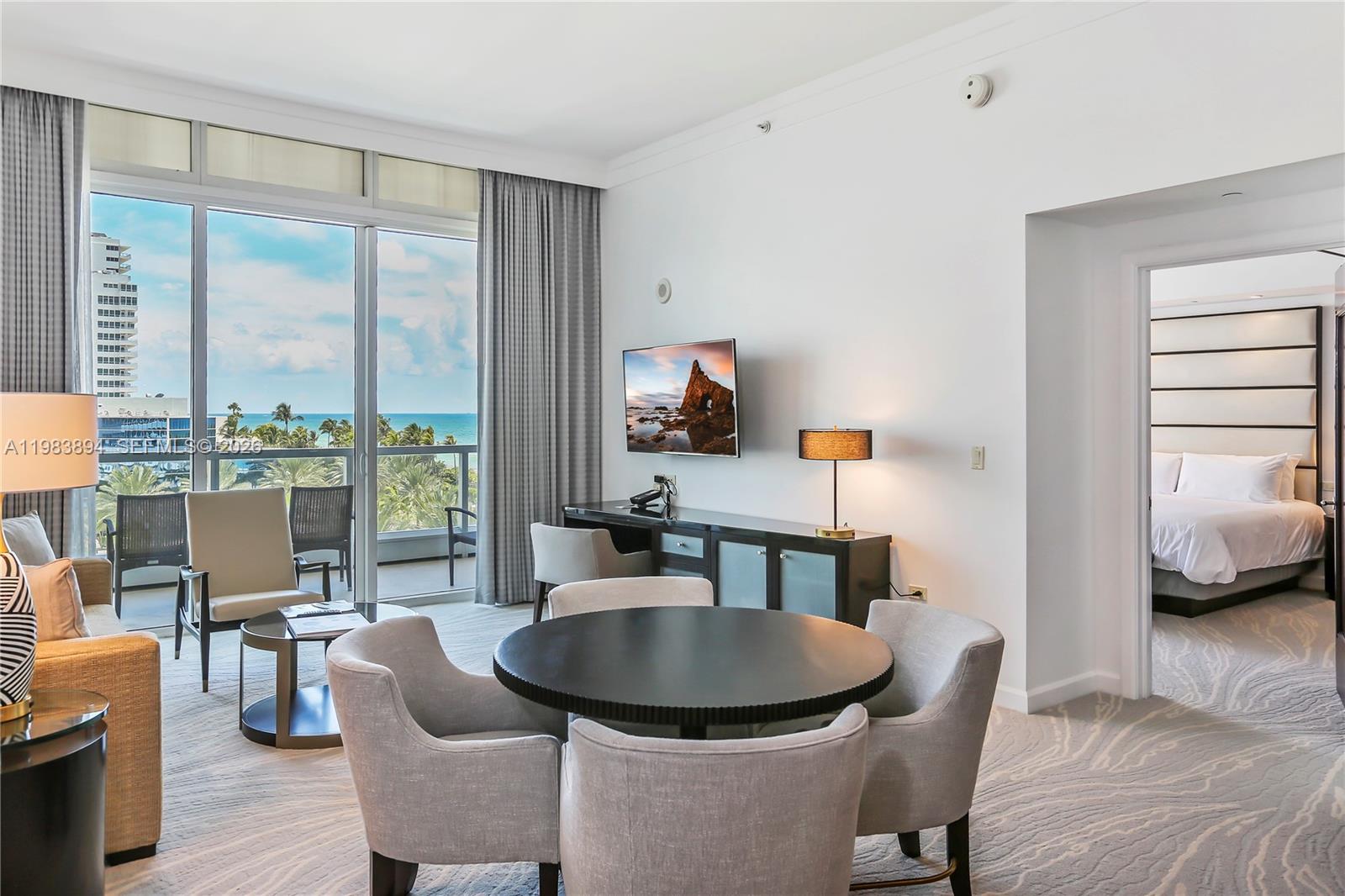 A living room with a dining table, desk, and balcony overlooking the ocean and city — 4391 Collins Ave, Miami Beach FL 33140, MIAMI BEACH, FL