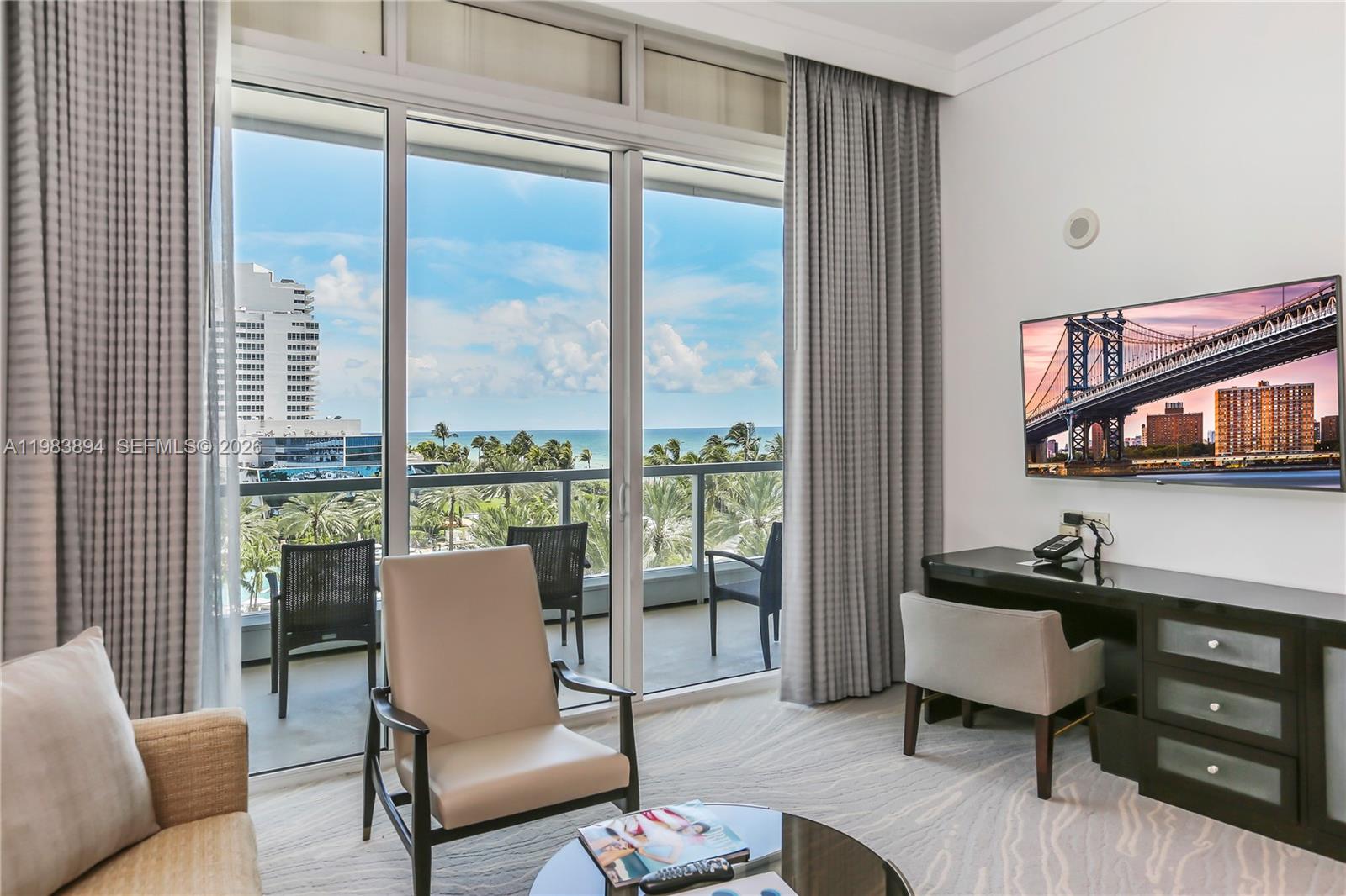 A hotel room features a desk, seating area, and floor-to-ceiling windows overlooking the ocean — 4391 Collins Ave, Miami Beach FL 33140, MIAMI BEACH, FL