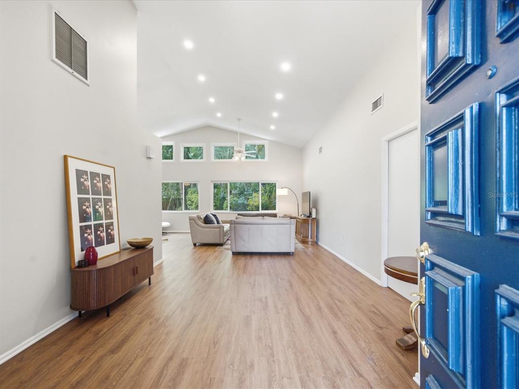 A view from an open blue door into a living room with vaulted ceilings — 419 WAYFARER COURT, TARPON SPRINGS, FL