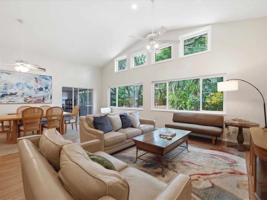 A living room with vaulted ceilings, large windows, a tan sofa, and a dining area — 419 WAYFARER COURT, TARPON SPRINGS, FL
