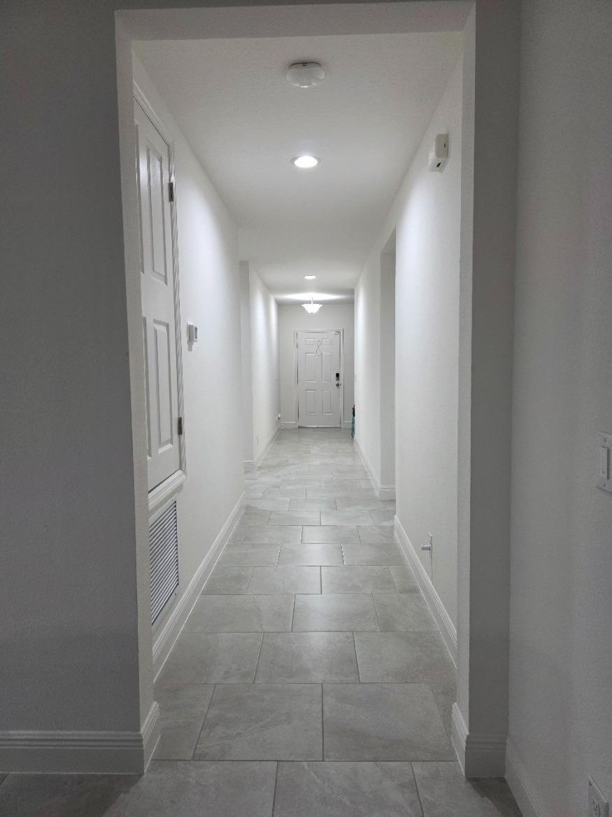 A long hallway with white walls, recessed lighting, and light gray tile flooring — 260 Hamlet Loop, Davenport FL 33837, DAVENPORT, FL