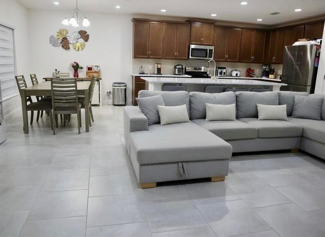 An open-concept kitchen and living area features gray tile flooring, dark wood cabinets, and furniture — 260 Hamlet Loop, Davenport FL 33837, DAVENPORT, FL