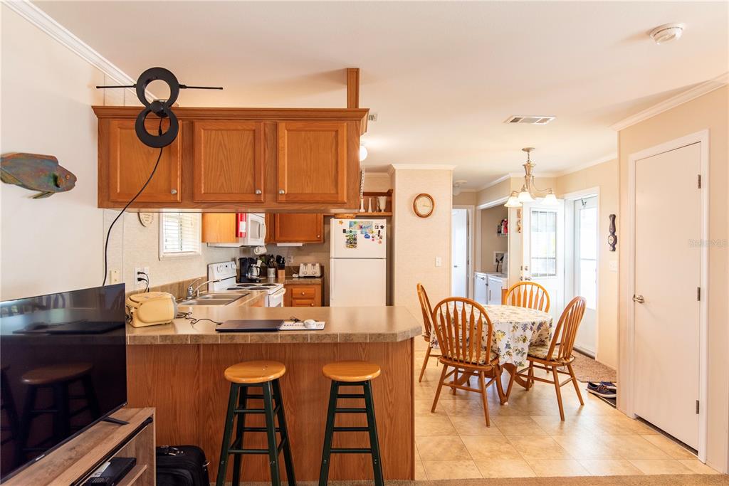 A kitchen with wooden cabinets, a breakfast bar with stools, and an adjacent dining area — 3 EDAM STREET, PUNTA GORDA, FL
