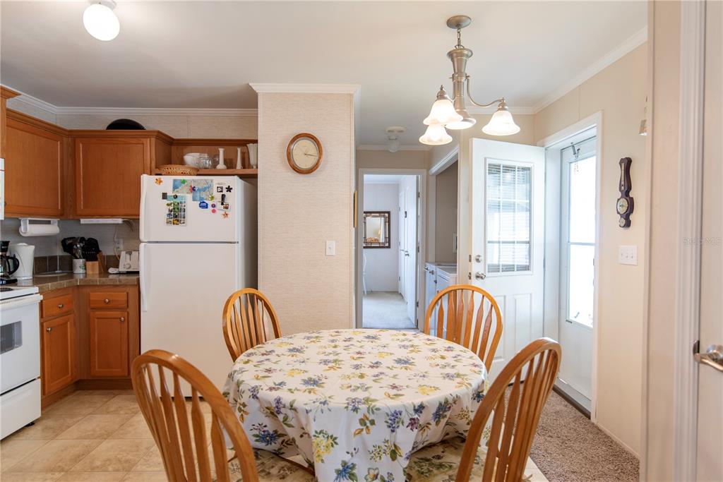 A kitchen and dining area with wooden cabinets, a round table, and a white refrigerator — 3 EDAM STREET, PUNTA GORDA, FL