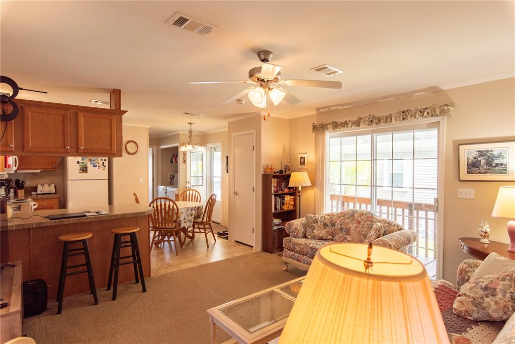 An open-concept living room and kitchen featuring a breakfast bar, dining area, and sliding doors — 3 EDAM STREET, PUNTA GORDA, FL