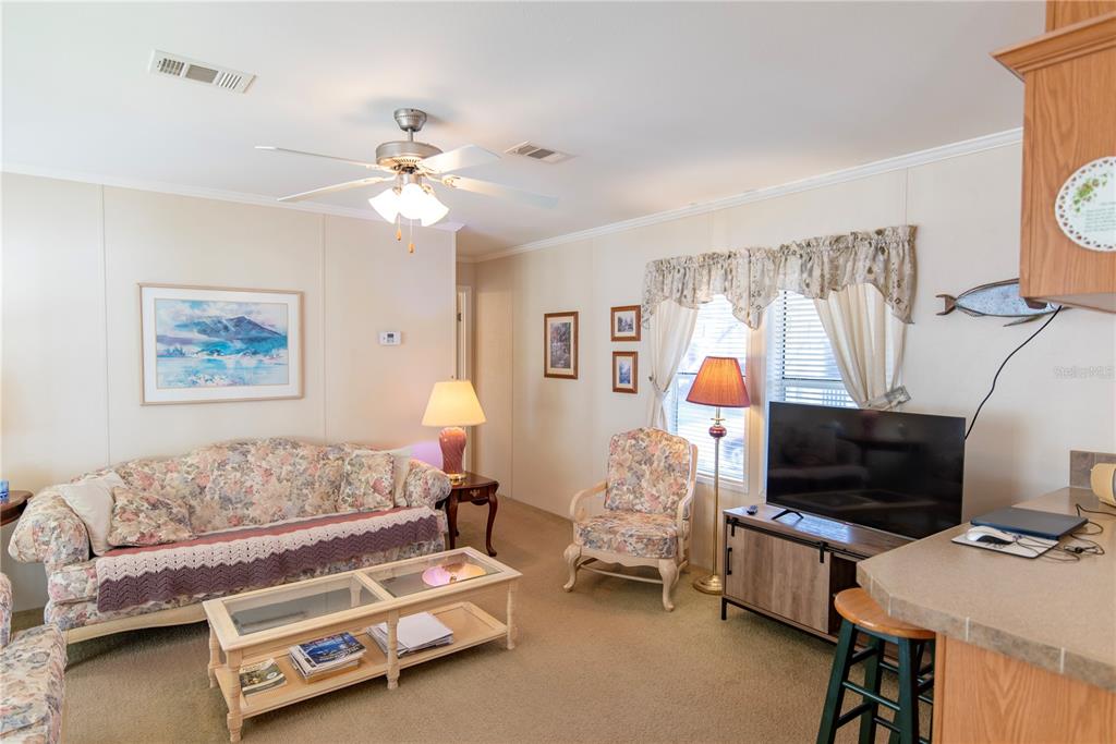 A living room features floral furniture, a glass-top coffee table, a television, and a ceiling fan — 3 EDAM STREET, PUNTA GORDA, FL