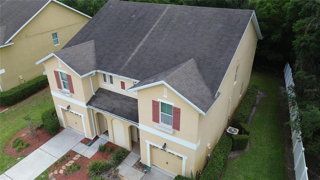An aerial view of a two-story tan house with a dark shingled roof and garages — 1111 PETERSON PLACE, SANFORD, FL