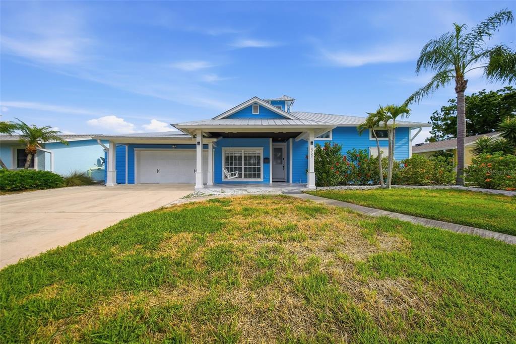 A bright blue single-story house features a metal roof, a covered porch, and a garage — 8722 PALISADES DRIVE, TAMPA, FL
