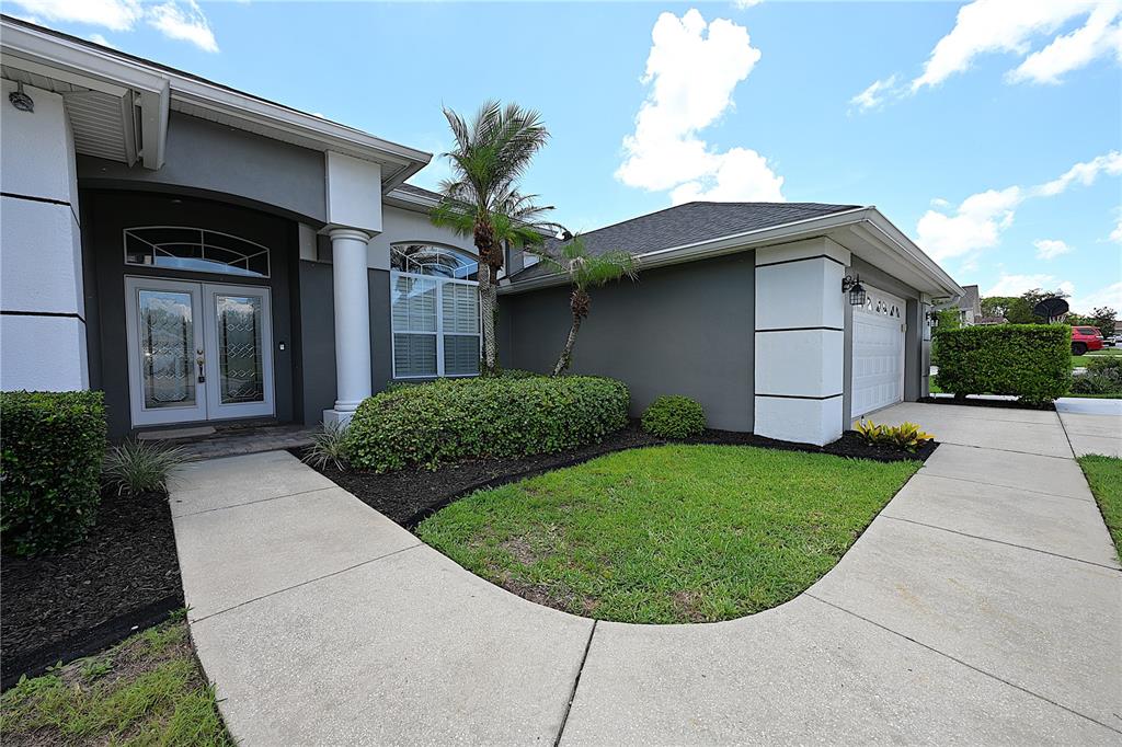 A gray house exterior features a double front door, white columns, and a concrete driveway — 2618 HIGH RIDGE DRIVE, LAKELAND, FL