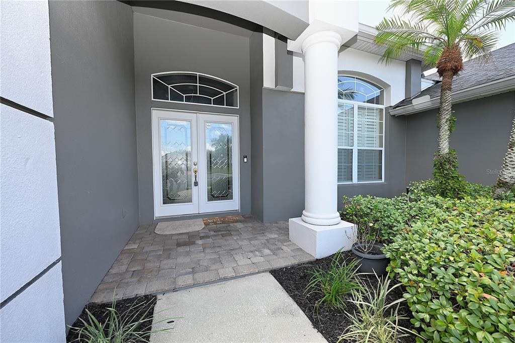 A paved entryway leads to a double front door with a white column and landscaping — 2618 HIGH RIDGE DRIVE, LAKELAND, FL