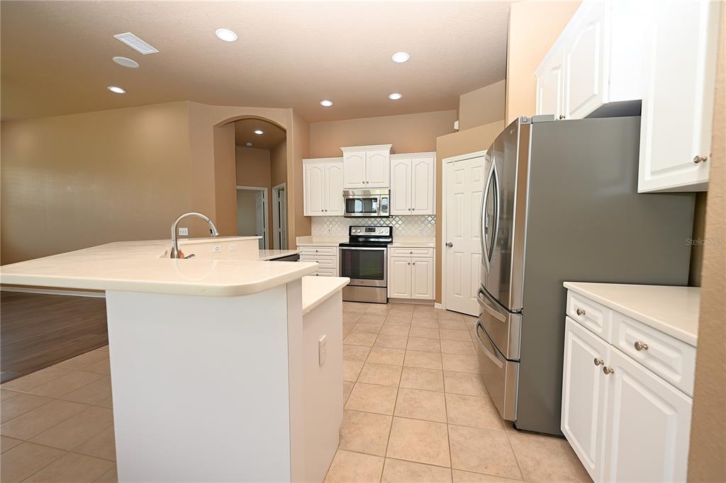 A kitchen with white cabinets, stainless steel appliances, and a breakfast bar island — 2618 HIGH RIDGE DRIVE, LAKELAND, FL