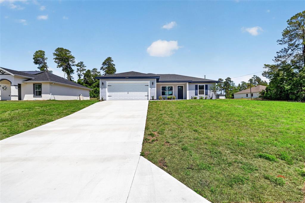 A single-story house with light blue siding, a white garage door, and a concrete driveway — 3101 NW BUENA VISTA ROAD, DUNNELLON, FL
