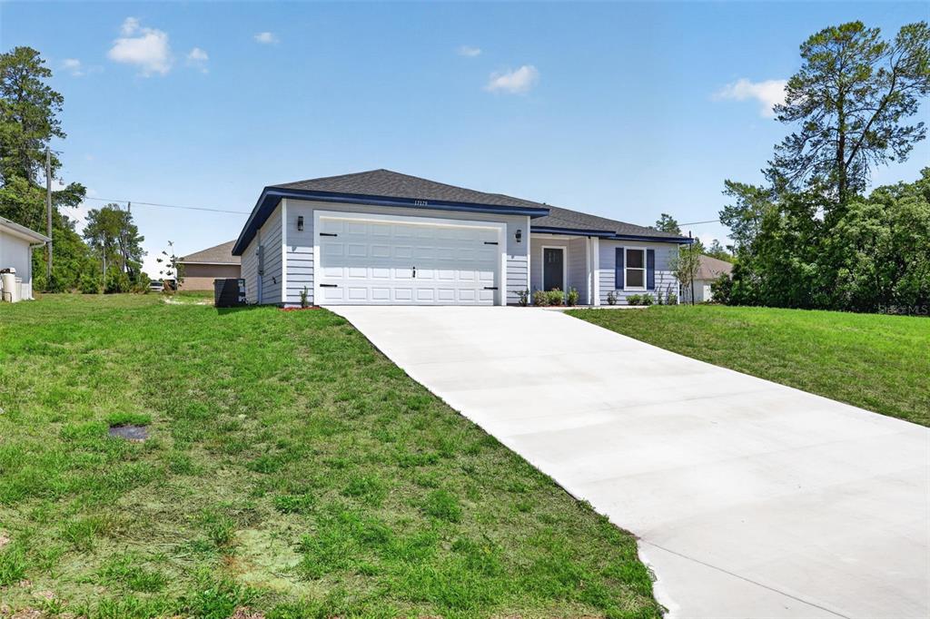 A single-story house with light blue siding, a two-car garage, and a concrete driveway — 3101 NW BUENA VISTA ROAD, DUNNELLON, FL