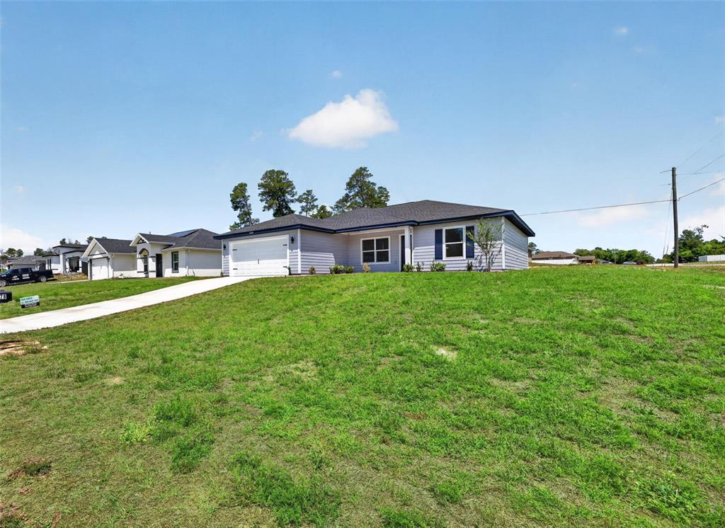 A light-colored, single-story suburban house sits on a grassy hill under a blue sky — 3101 NW BUENA VISTA ROAD, DUNNELLON, FL