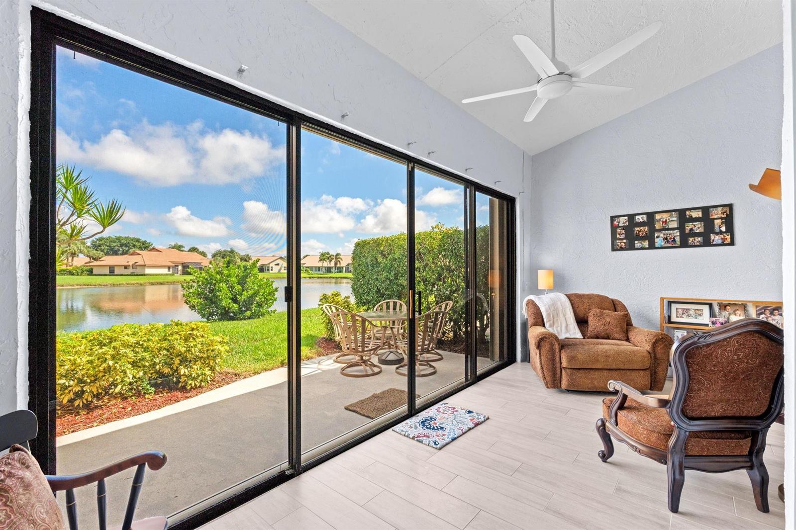 A sunroom with tile floors, a ceiling fan, and sliding glass doors overlooking a lake — 8486 Heather Place, Boynton Beach FL 33472, BOYNTON BEACH, FL