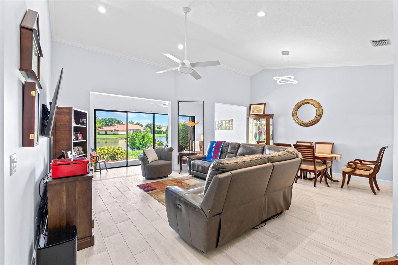 A living room with tile floors, a gray sectional sofa, and sliding doors overlooking a lake — 8486 Heather Place, Boynton Beach FL 33472, BOYNTON BEACH, FL