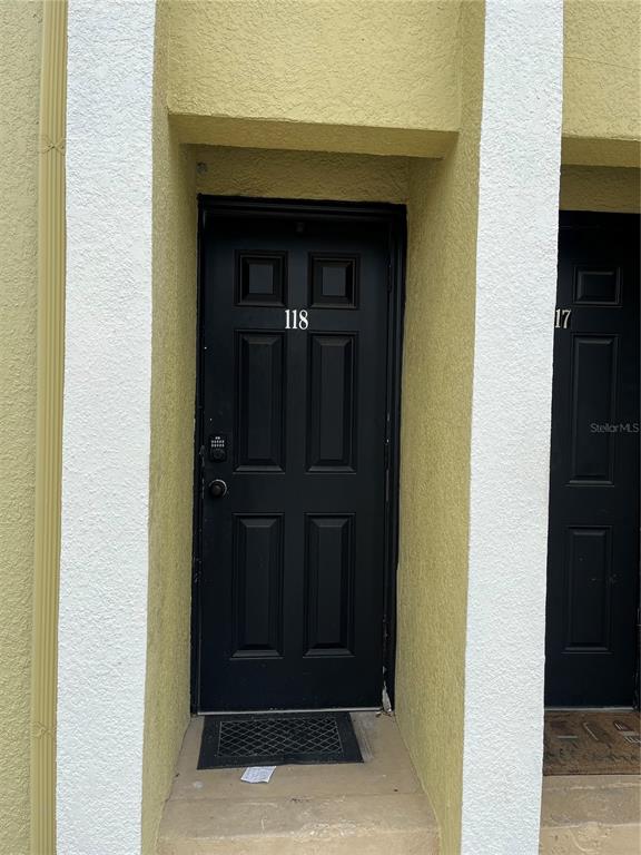 A black front door with the number 118 is set within a yellow stucco exterior — 3206 W AZEELE STREET UNIT 118, TAMPA, FL