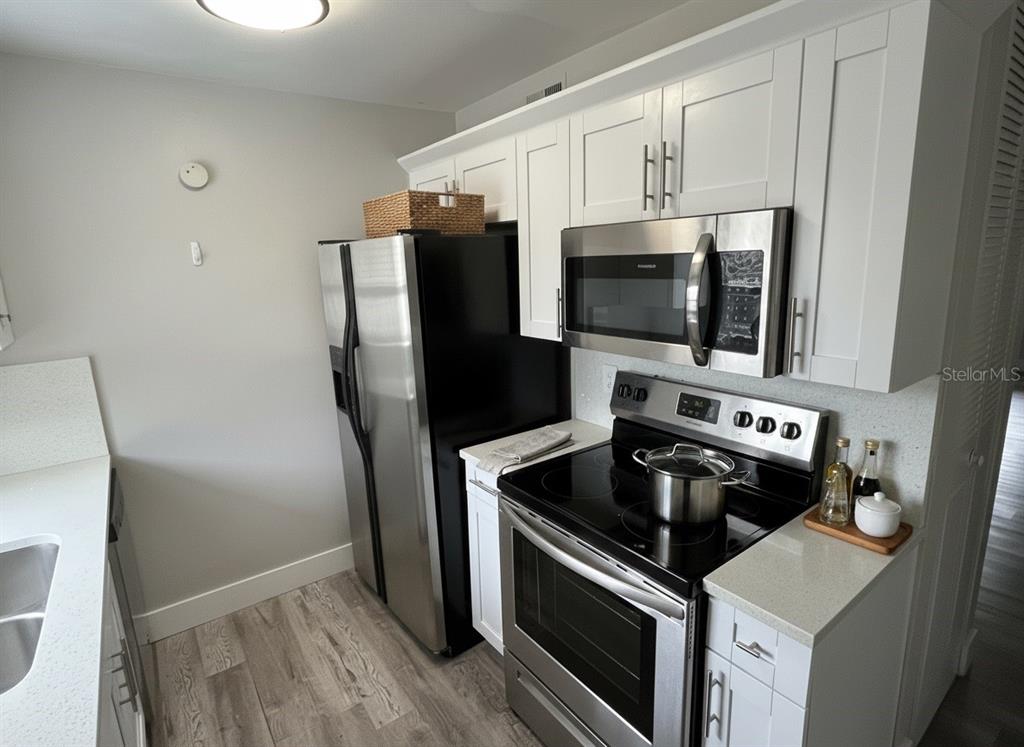A kitchen features white cabinets, stainless steel appliances, and light-colored countertops — 3206 W AZEELE STREET UNIT 118, TAMPA, FL