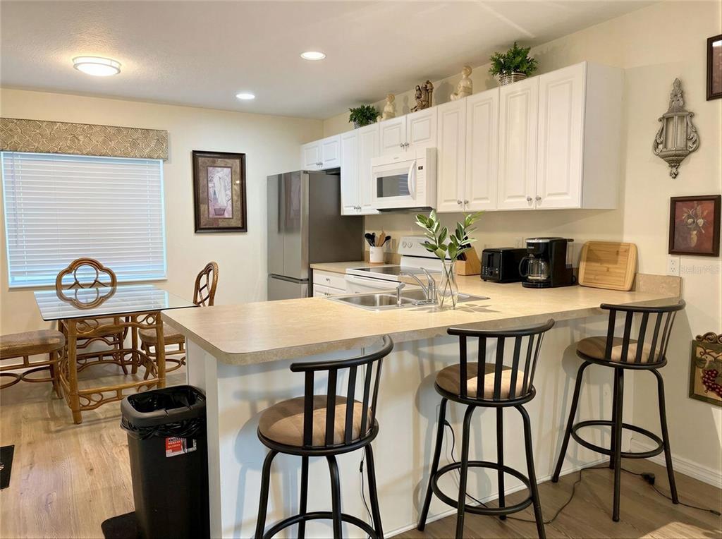A kitchen features white cabinets, stainless steel appliances, a breakfast bar, and a dining area — 4029 60TH STREET W, BRADENTON, FL
