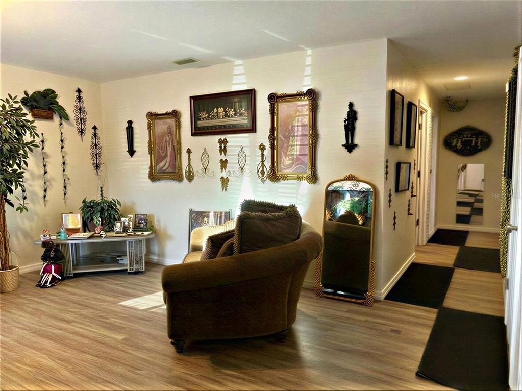 A living room features wood-look flooring, a brown armchair, and decorative wall art — 4029 60TH STREET W, BRADENTON, FL